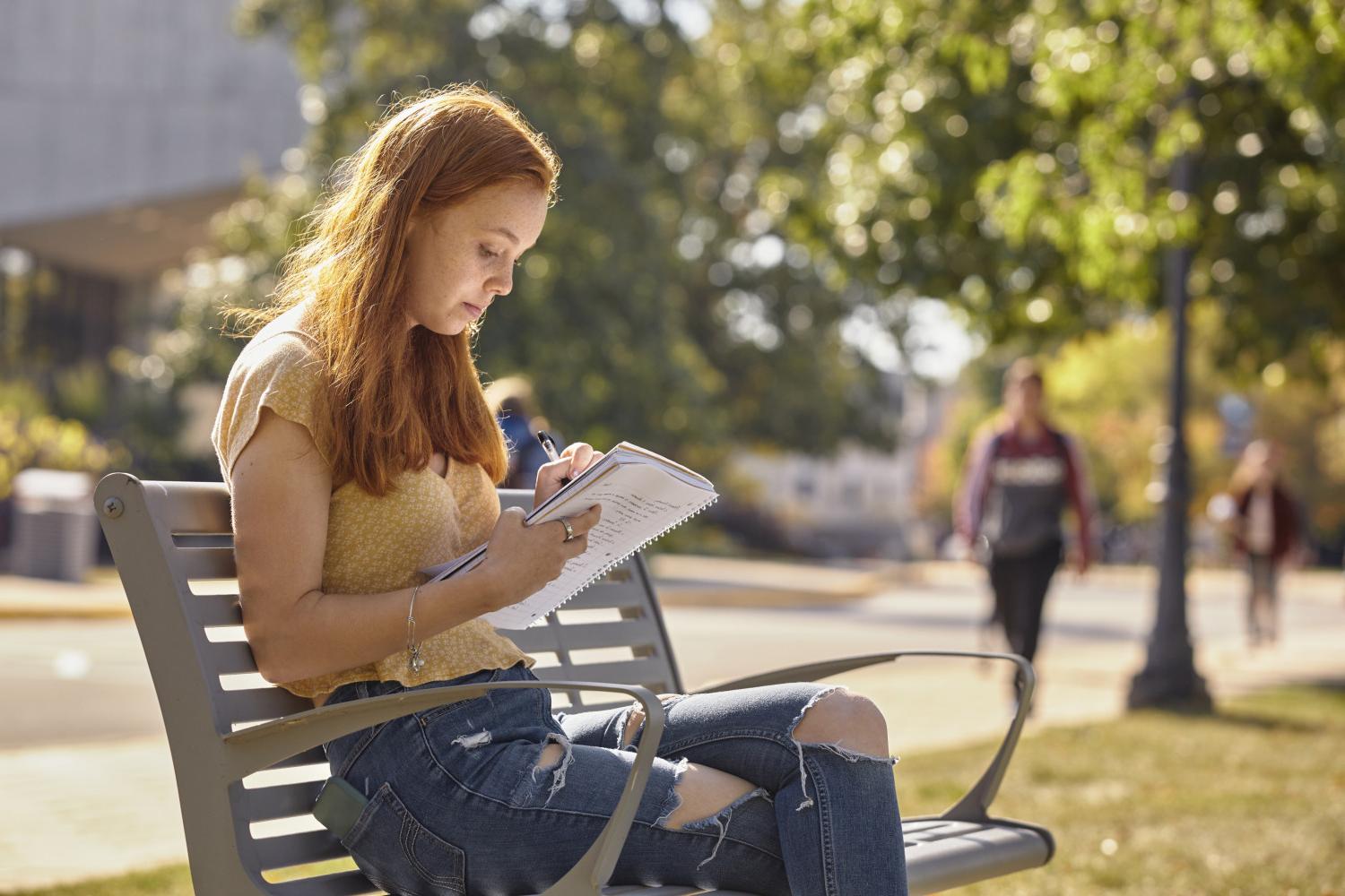 A <a href='http://kjj.tincyn.net'>全球十大赌钱排行app</a> student reads on a bench along Campus Drive.